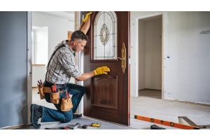 Contractor installing a decorative wood interior door with glass panel in a home remodel setting