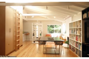 Mid century modern open plan living space with light oak cabinet wall and exposed beams
