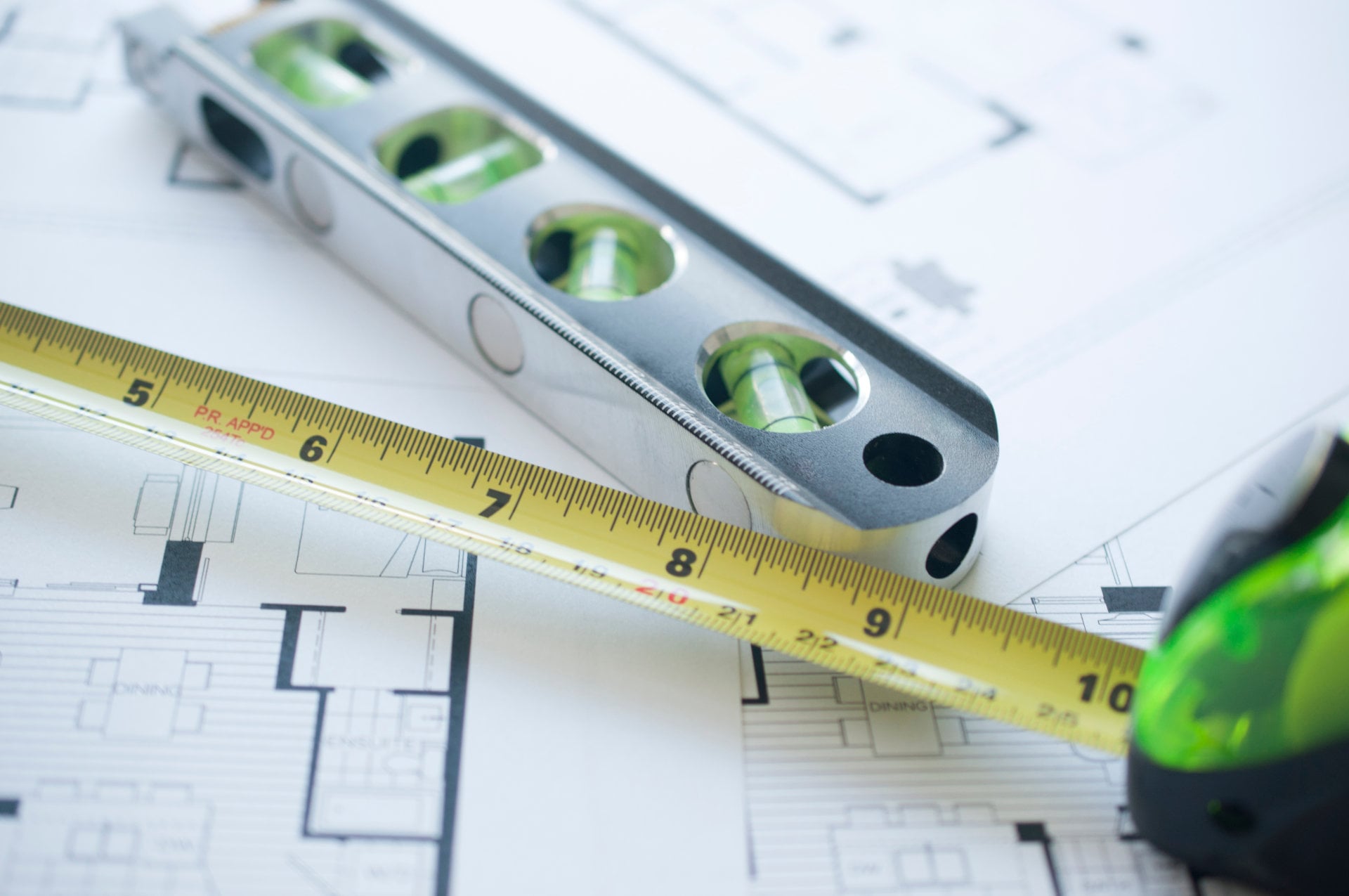 Essential measuring tools including tape measure and level on kitchen blueprints for RTA cabinet installation