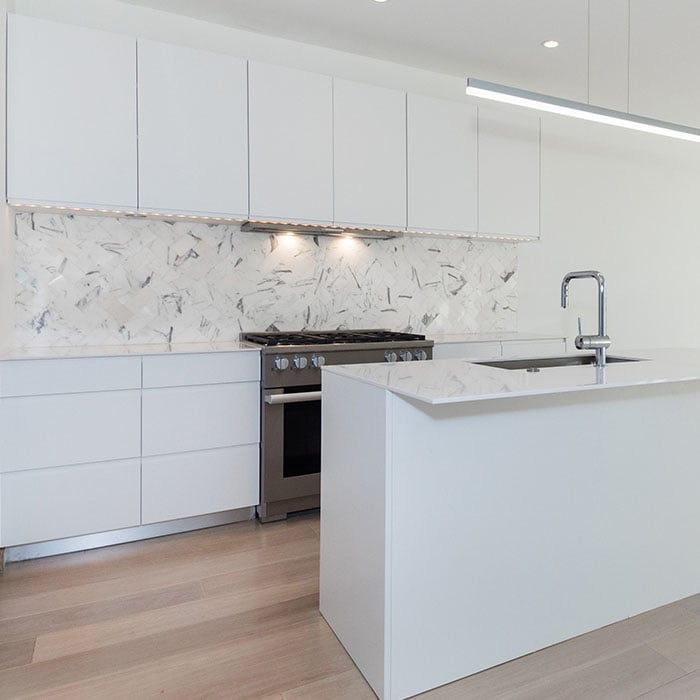 Modern European kitchen featuring lacquered white cabinet doors and gas range