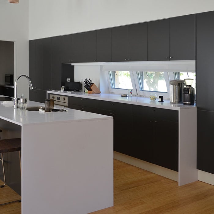 Matte black kitchen cabinetry with white countertops and integrated window view