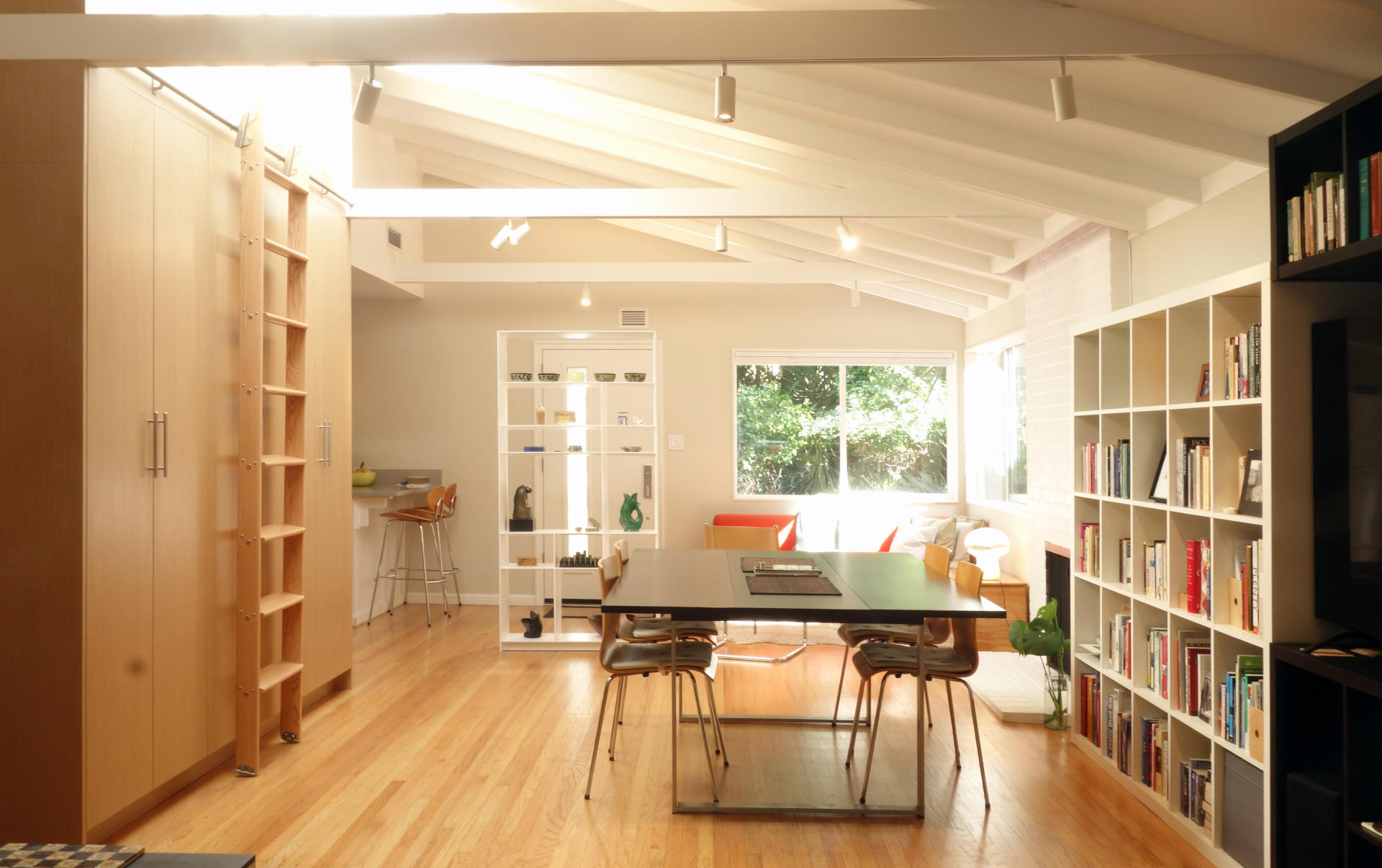 Mid century modern open plan living space with light oak cabinet wall and exposed beams