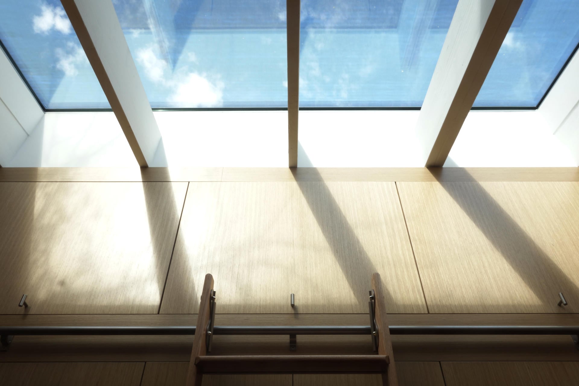 Light oak wood veneer cabinet doors under skylight with natural shadows